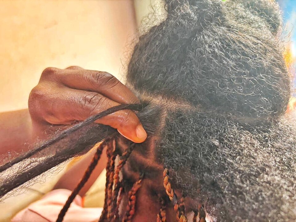 Close-up of skilled hands braiding natural hair with extensions